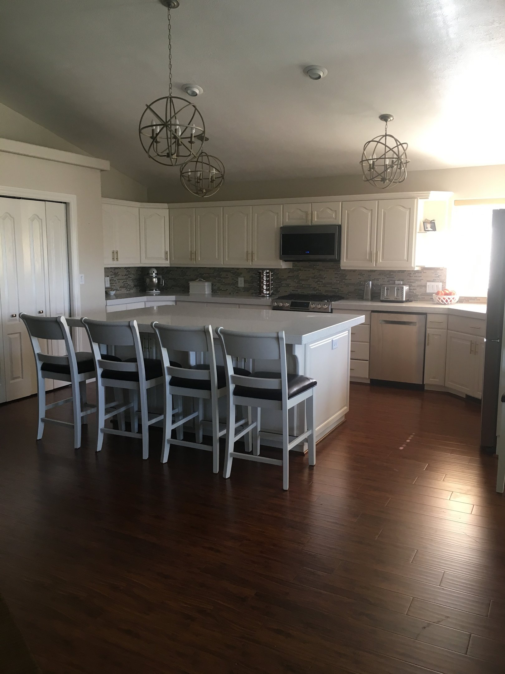 White kitchen with island, custom cabinets, and modern lighting