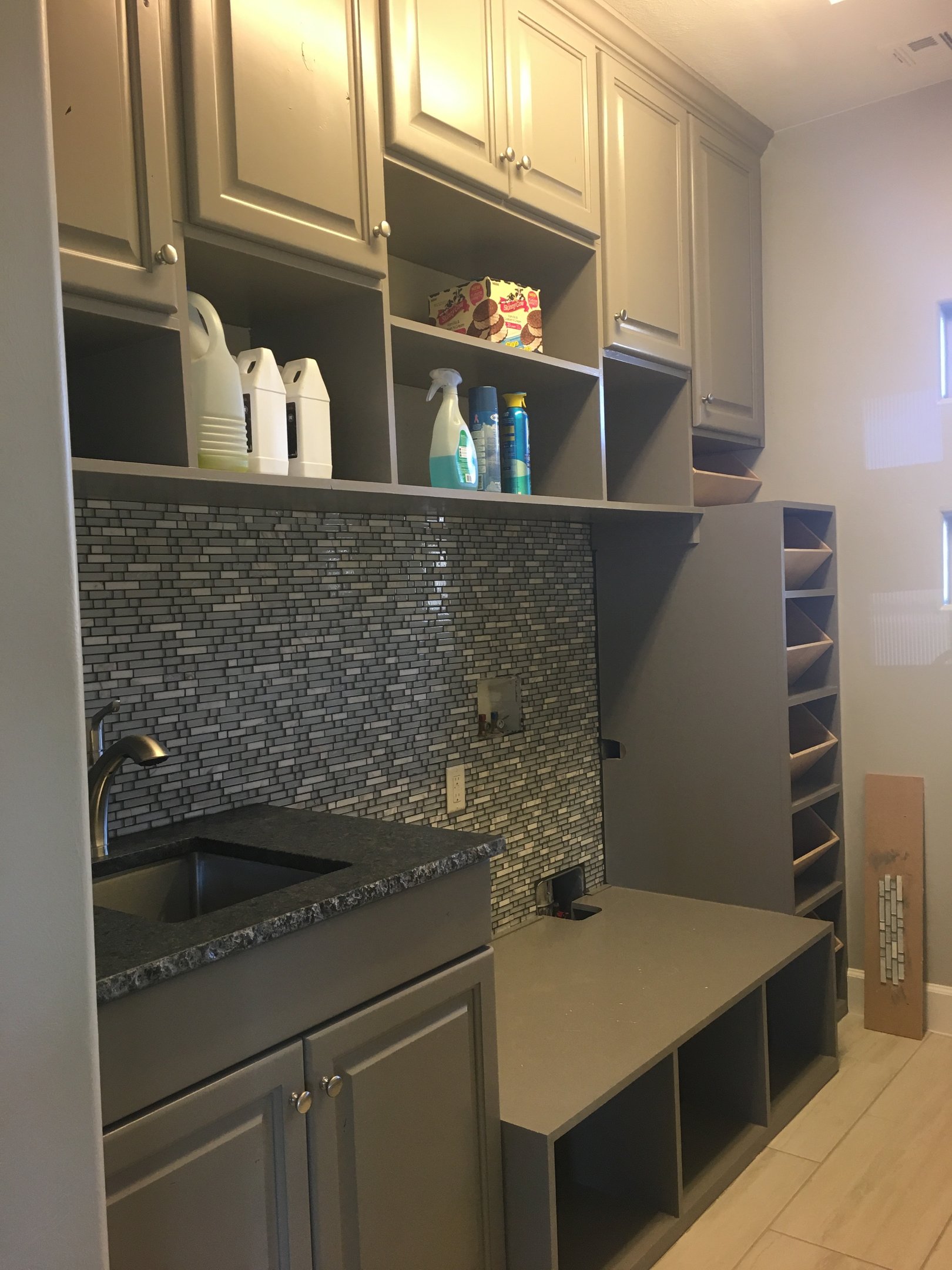Gray utility or beverage cabinetry with wine storage and backsplash