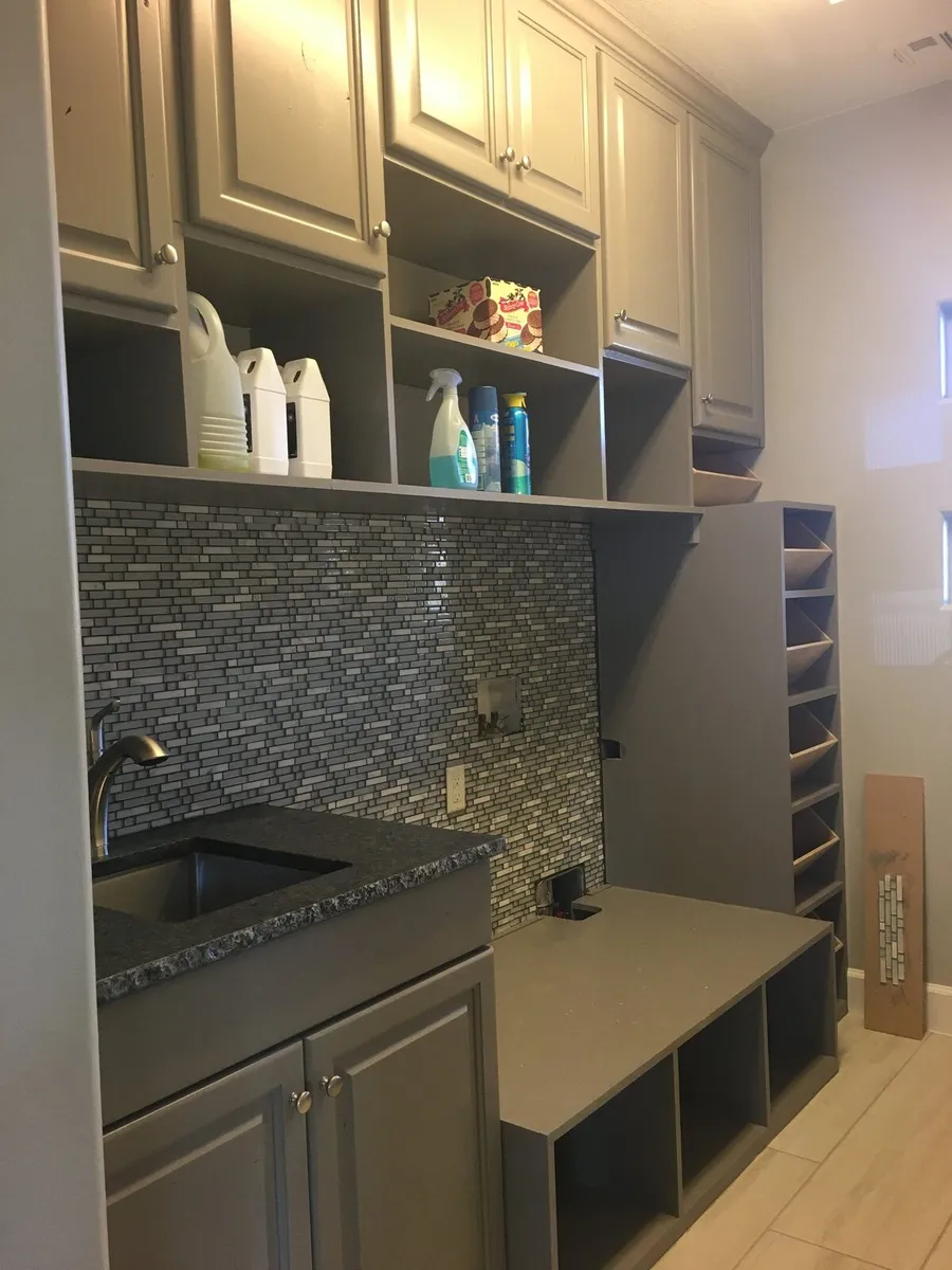 Gray utility or beverage cabinetry with wine storage and backsplash