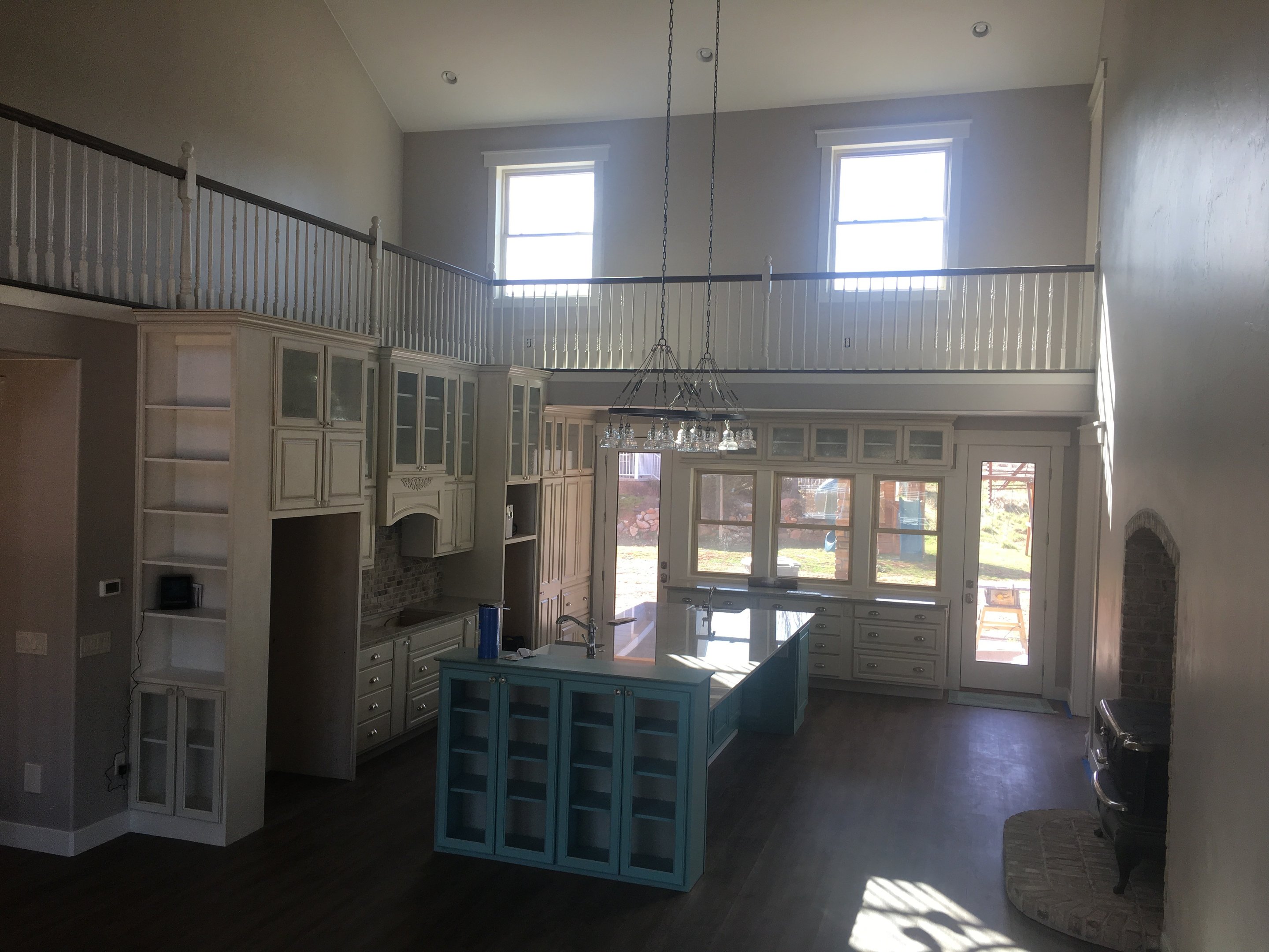 Large kitchen with tall cabinetry, white perimeter cabinets, and a blue island