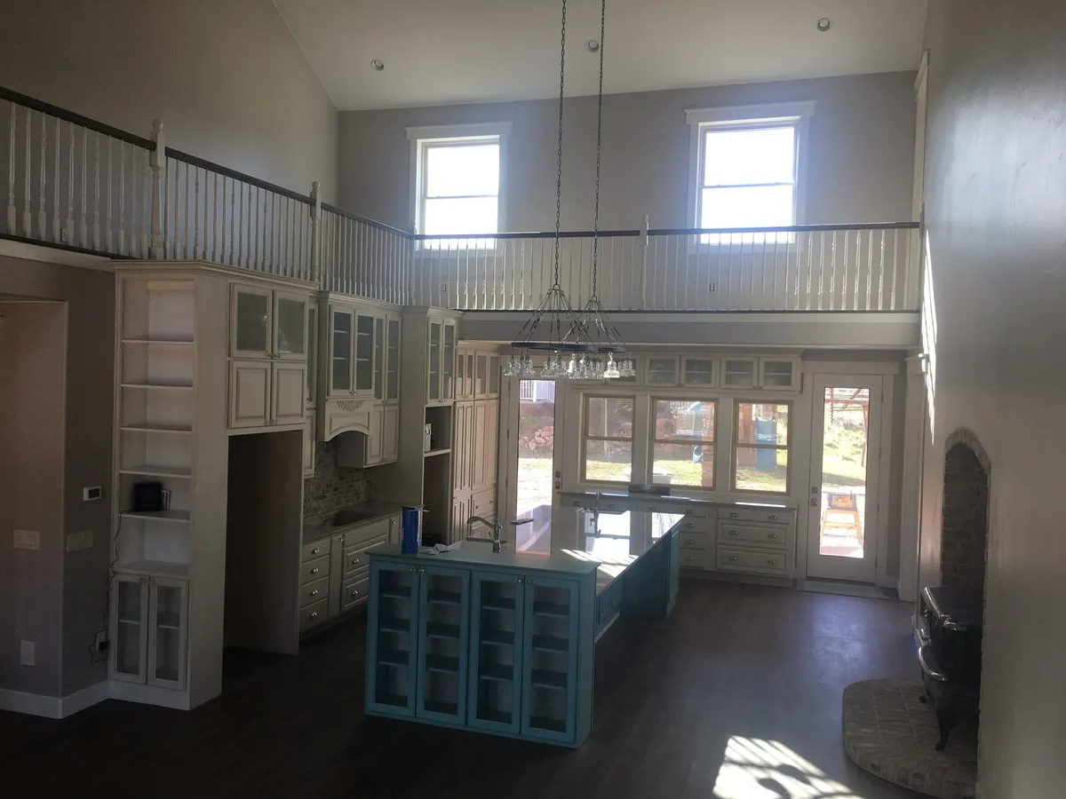 Large kitchen with tall cabinetry, white perimeter cabinets, and a blue island